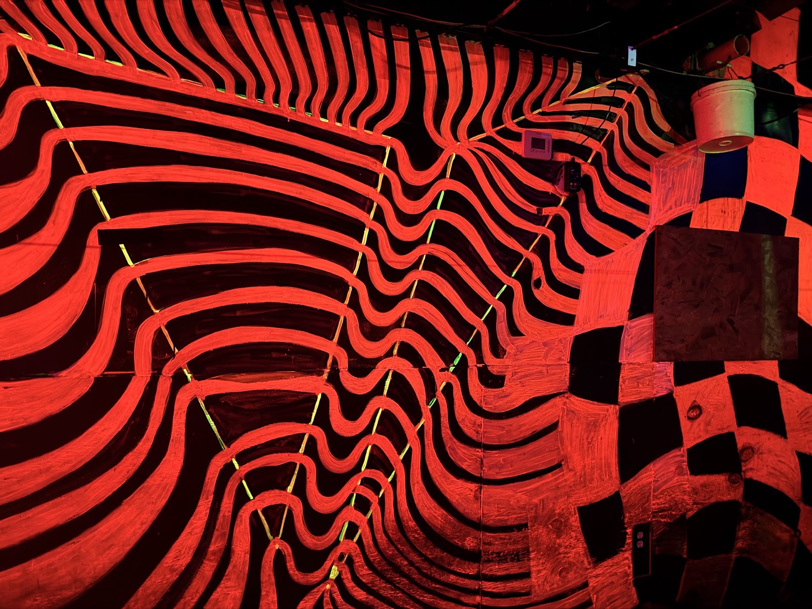 A wall of red wavy stripes melting into a black-and-red checkerboard