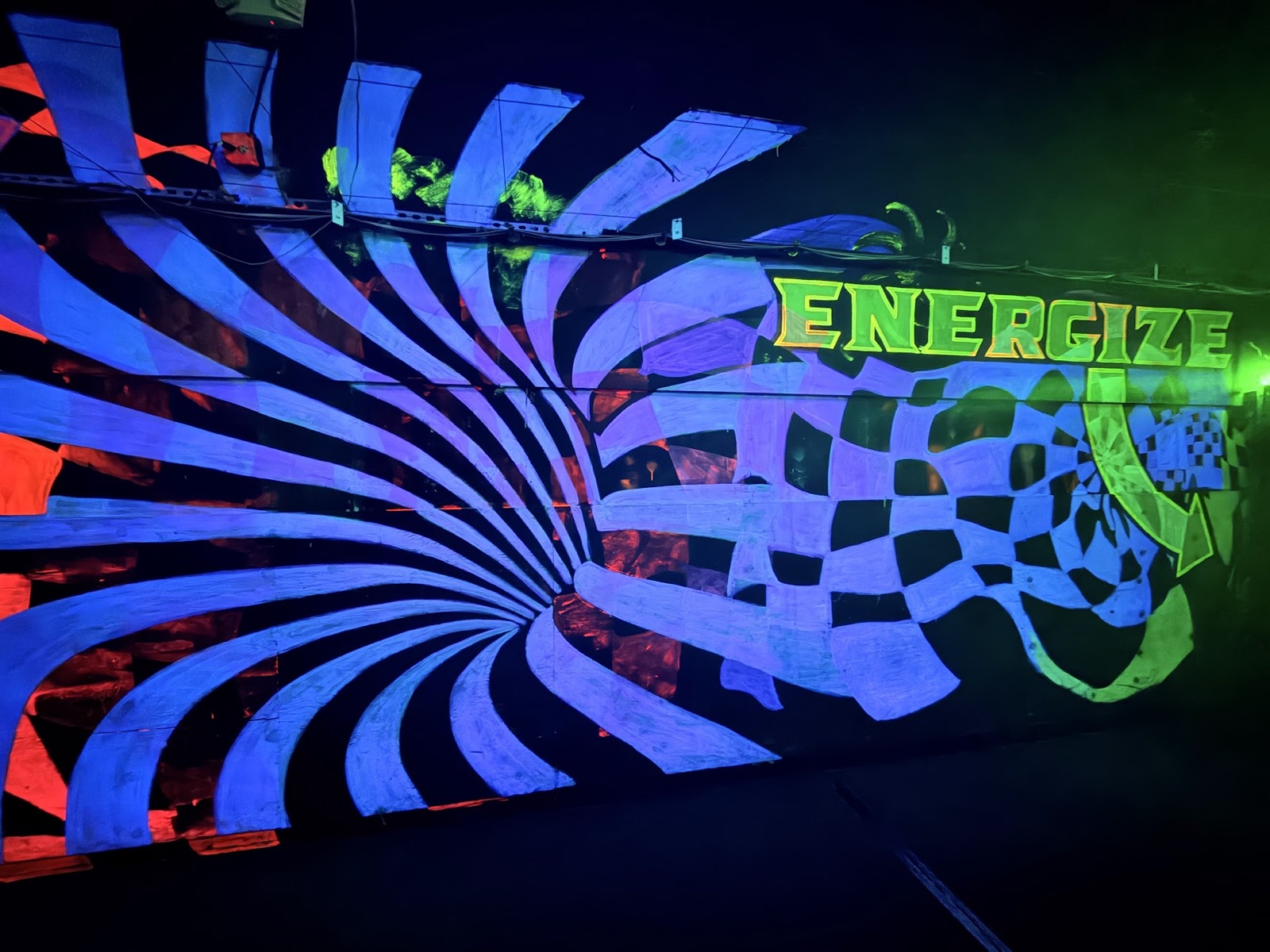 A blue-and-white vortex blending into a checkerboard under a glowing green "ENERGIZE" sign